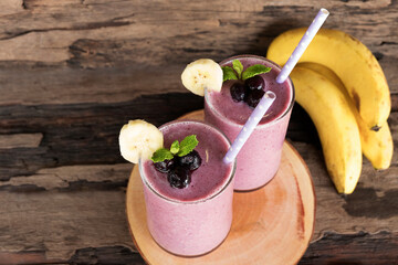 Blueberry mix banana smoothies purple colorful fruit juice milkshake blend beverage healthy high protein taste yummy drink in glass morning on wooden background.