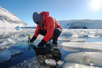 Climate scientist in Arctic gear takes an ice core sample on a melting glacier, with pools of water and retreating ice in the background.