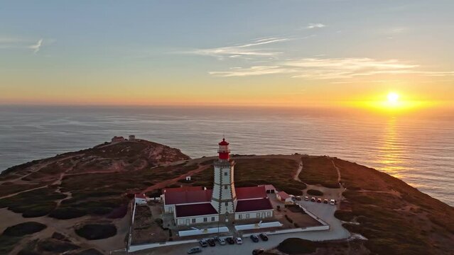 Aerial drone view of farol lighthouse on Cabo Espichel cape Espichel on Atlantic ocean at sunset. Sesimbra, Portugal. Orbit parallax shot