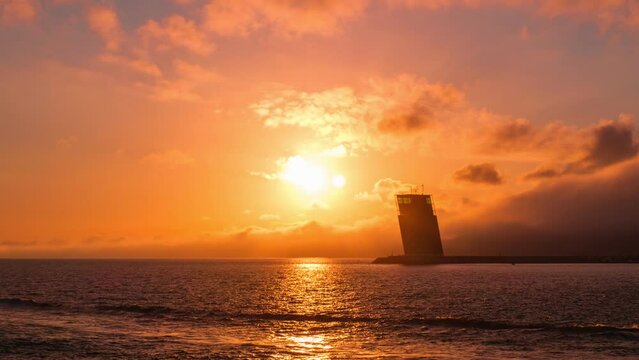 Time-lapse of Torre VTS de Lisboa, VTS Vessel Traffic Systemtower, Centre for Coordination and Control of Maritime Traffic and Safety of Lisbon on bank of Tagus river, Portugal on sunset. Zoom in