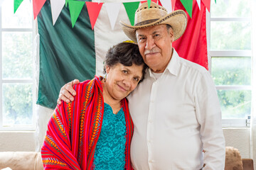 Portrait of an elderly couple posing in front a Mexican flag