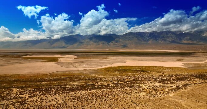 Varied types of land in the desert of California. Gorgeous bare rocks are at background shadowed by clouds. Top view on Death Valley.
