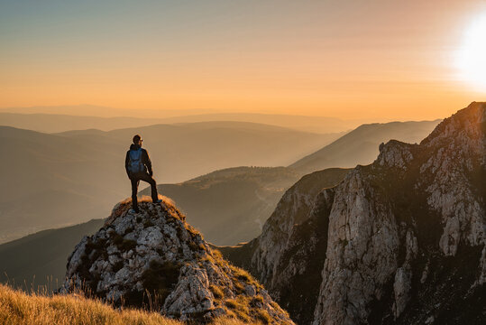 A man who hikers enjoys a break look at the top of the mountain at sunset adventure travel.