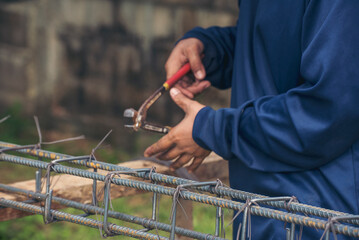 Construction Worker hands using pincer pliers iron wire. Outdoor Worker using wire bending pliers, construction work. Men hands bending cutting steel wire fences bar reinforcement of concrete work - obrazy, fototapety, plakaty
