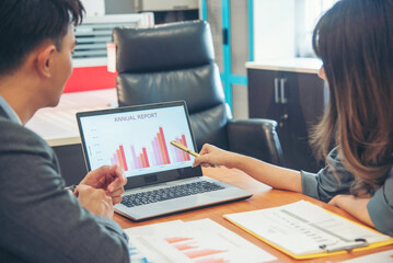 Two businesspeople meeting team discuss using laptop look at financial graph chart in office desk. Two young businessman reading Planning analyze marketing infographic. Partners team working together