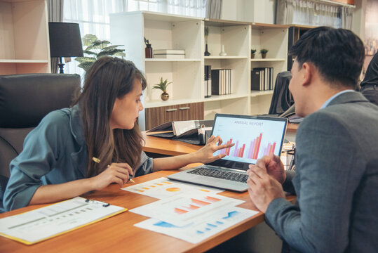 Two businesspeople meeting team discuss using laptop look at financial graph chart in office desk. Two young businessman reading Planning analyze marketing infographic. Partners team working together - Powered by Adobe