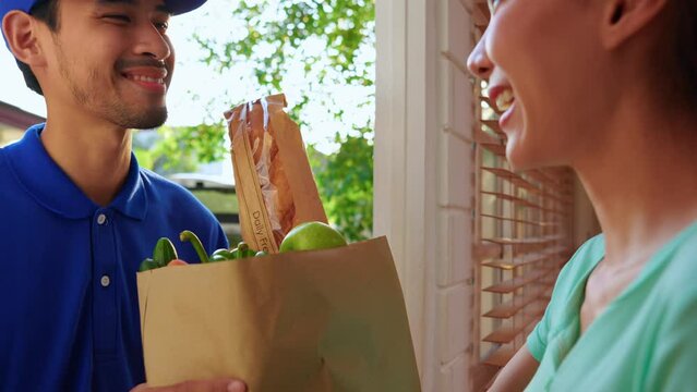 Asian young delivery man delivering package to female customer at home.