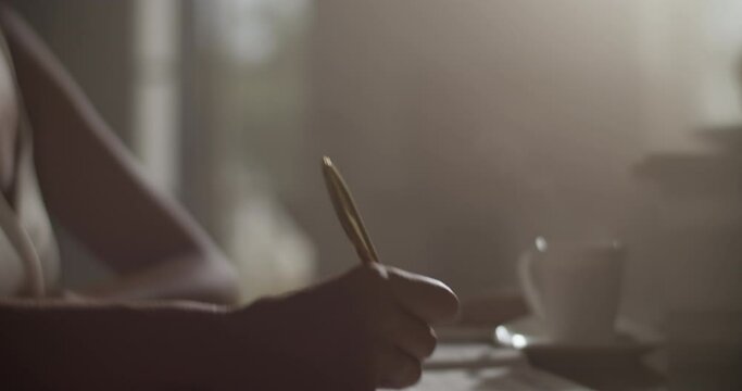 Focused female composer composing music in darkness with dim sunlight