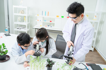 A boy and a girl are in the lab. Microscopic study There is a teacher giving advice.