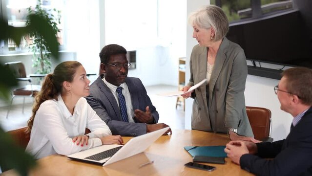 Positive partner men and women discussing a problem sitting around table in meeting room