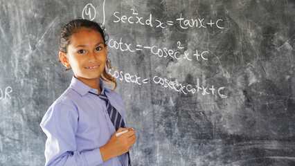 Happy Rural School Girl wearing School Uniform Standing in Front of A Black Board.