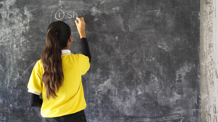 Happy Rural School Girl wearing School Uniform Standing in Front of A Black Board.