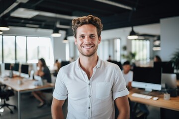 Fototapeta premium Smiling portrait of a happy young caucasian man working for a modern startup company in a business office