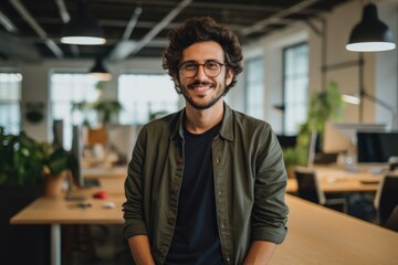 Smiling portrait of a happy young caucasian man working for a modern startup company in a business office