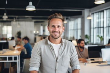 Fototapeta premium Smiling portrait of a happy young caucasian man working for a modern startup company in a business office