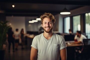 Fototapeta premium Smiling portrait of a happy young caucasian man working for a modern startup company in a business office