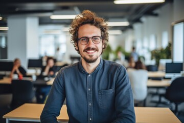 Fototapeta premium Smiling portrait of a happy young caucasian man working for a modern startup company in a business office
