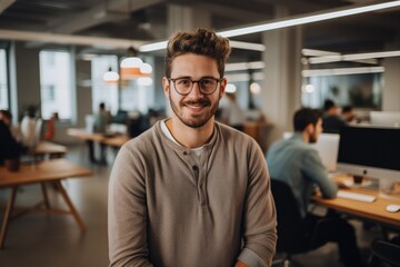 Obraz premium Smiling portrait of a happy young caucasian man working for a modern startup company in a business office