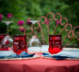 Festive outdoor dining table with wine and red water glasses decorative chair in background - 646204462