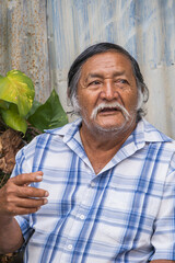 Old latino man speaking in front of camera, sitting