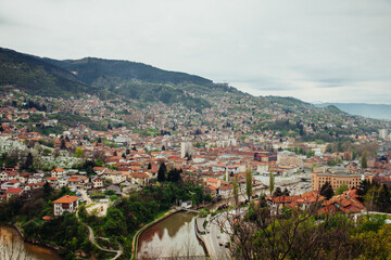 Fototapeta na wymiar Panoramic view of the spring city of Sarajevo, Bosnia and Herzegovina. A trip to a European Balcan city in the mountains with orange roofs