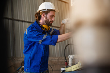 Industrial engineer wearing a white helmet working in industrial factory.