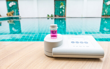 Quality water analysis tool on swimming pool edge with space on water background, measure chlorine...