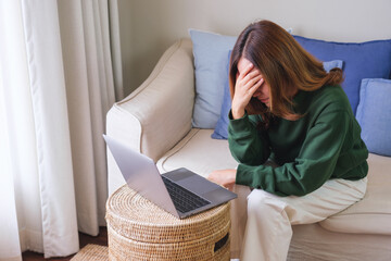 A woman get headache and stressed while working online on laptop computer at home