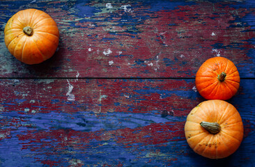 Bright orange pumpkins on a red and blue crafting wooden background. Conceptual background for Harvest Day, Halloween and Thanksgiving