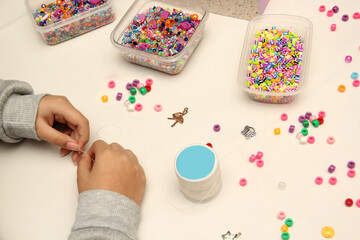 Teenage woman's hands make friendship bracelets to distribute and exchange with her friends