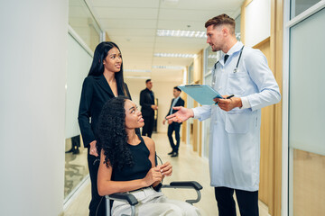 Male doctor in white medical uniform consult female patient on consultation. They Consult Digital Tablet Computer while Talking about Patient's Health.