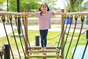 Little kid girl asian  while enjoying on the playground. Which increases the development and...