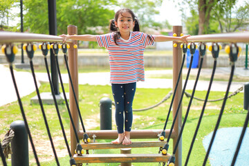 Fototapeta premium Little kid girl asian while enjoying on the playground. Which increases the development and enhances outside the classroom learning skills concept.