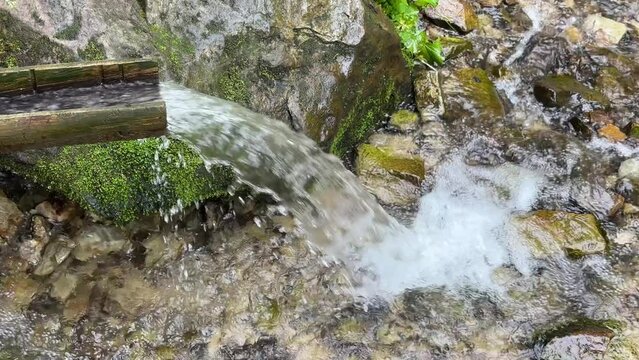 Water that flows from the spring in the mountains and descends through a gutter. Source of pure mineral water in the mountains view from above