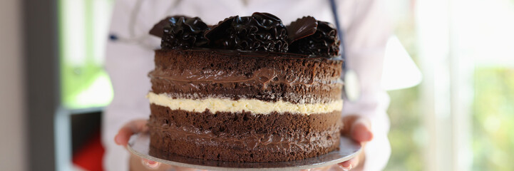Dietologist holds whole chocolate cake and warns against overeating.