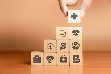 Wooden health icon cubes stacked in layers on a wooden surface with an orange background