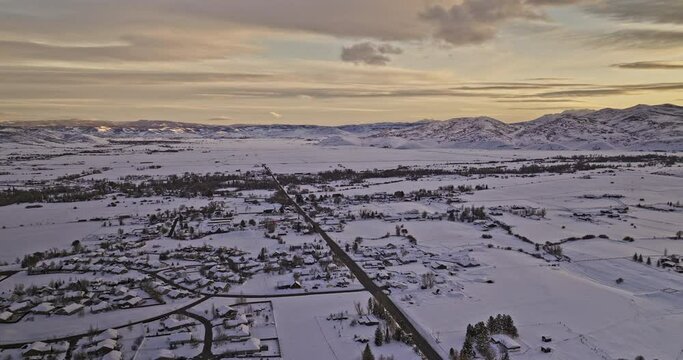 Oakley Utah Aerial v3 panoramic panning view drone flyover town area blanketed in a vast expanse of glistening snowfields and pristine mountainscape at sunset - Shot with Mavic 3 Cine - February 2023