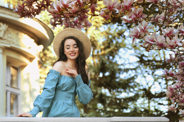 Beautiful woman near blossoming magnolia tree on spring day