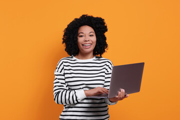 Happy young woman with laptop on orange background