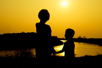 Silhouette of a family comprising a father, mother and two children happy family the sunset.Concept of friendly 