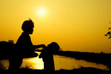 Silhouette of a family comprising a father, mother and two children happy family the sunset.Concept of friendly  - 646230064