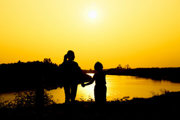 Fototapeta na wymiar Silhouette of a family comprising a father, mother and two children happy family the sunset.Concept of friendly 