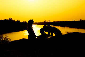 Silhouette of a family comprising a father, mother and two children happy family the sunset.Concept of friendly 