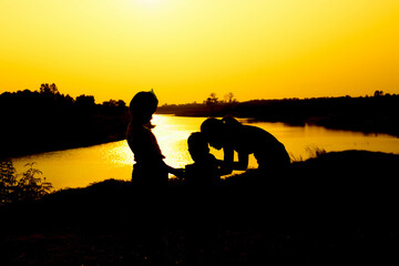 Silhouette of a family comprising a father, mother and two children happy family the sunset.Concept of friendly  - 646230292