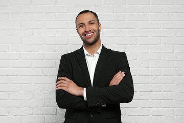 Young businessman in formal outfit near white brick wall