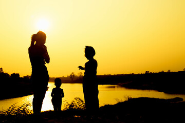Silhouette of a family comprising a father, mother and two children happy family the sunset.Concept of friendly  - 646230403