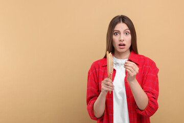 Emotional woman untangling her lost hair from brush on beige background, space for text. Alopecia...
