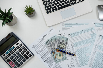 Deadline concept 1040 tax form with laptop calculator and dollar bills on office desk