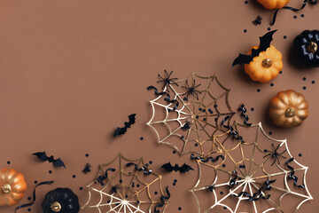 Halloween holiday background with party decorations from pumpkins, bats, spider web and ghosts with confetti and ribbon top view. Happy halloween greeting card flat lay style..