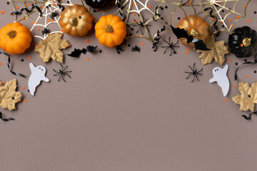 Halloween holiday background with party decorations from pumpkins, bats, spider web and ghosts top view. Happy halloween greeting card flat lay style..